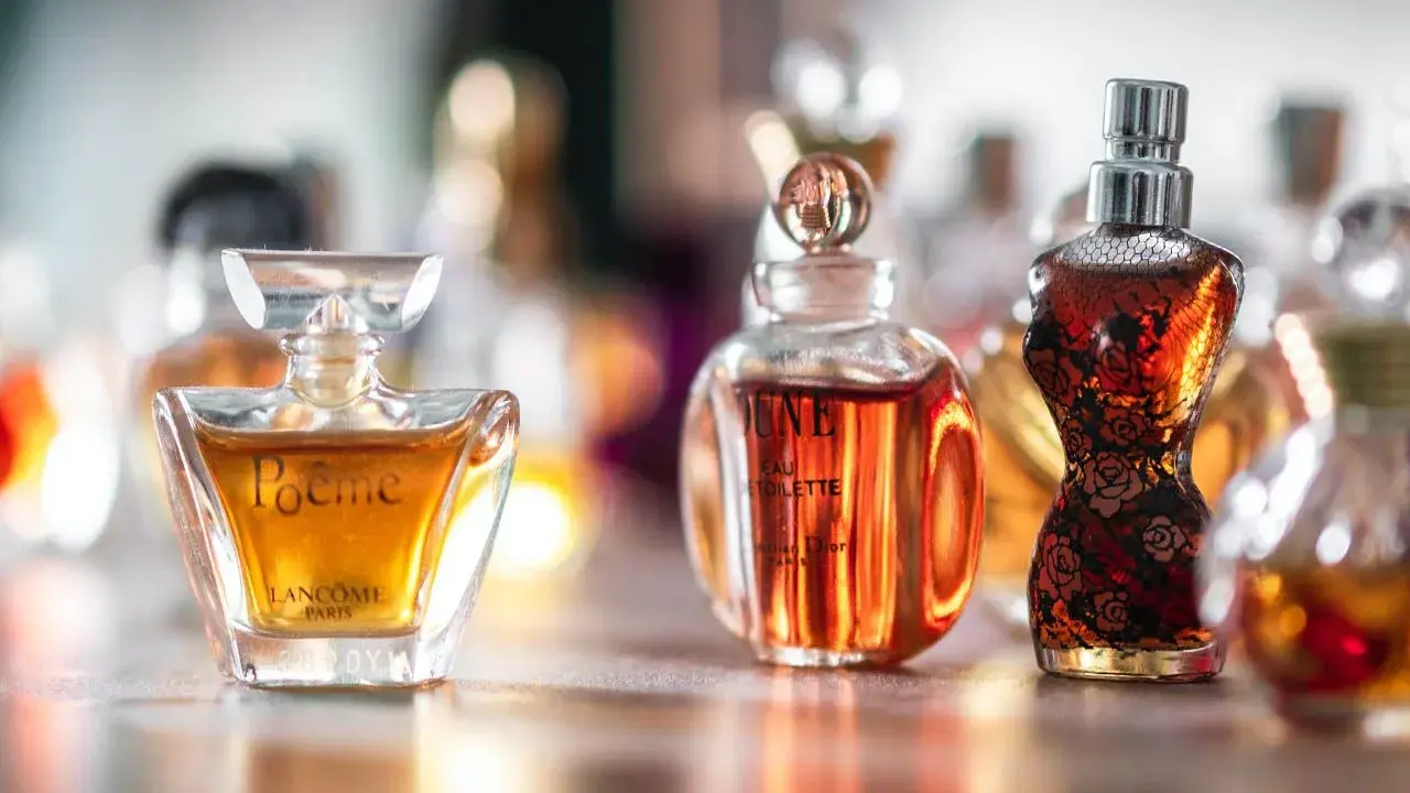 Kolekcja damskich perfum z lat 90. w szklanych flakonach, w tym Poeme Lancome i Dune Dior.