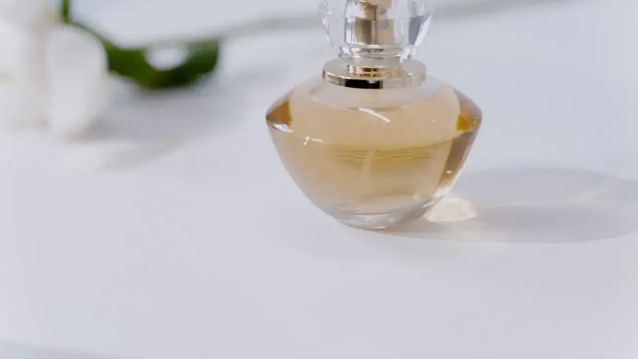 Elegancka butelka perfum na białym tle. Chcesz wiedzieć, jak sprawdzić, czy perfumy są oryginalne? Zwróć uwagę na detale.