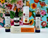 Kremy z filtrem SPF 30 i SPF 50, olejek z pestek malin i krem ochronny z dwutlenkiem tytanu na tle tropikalnych kwiatów i motyli.