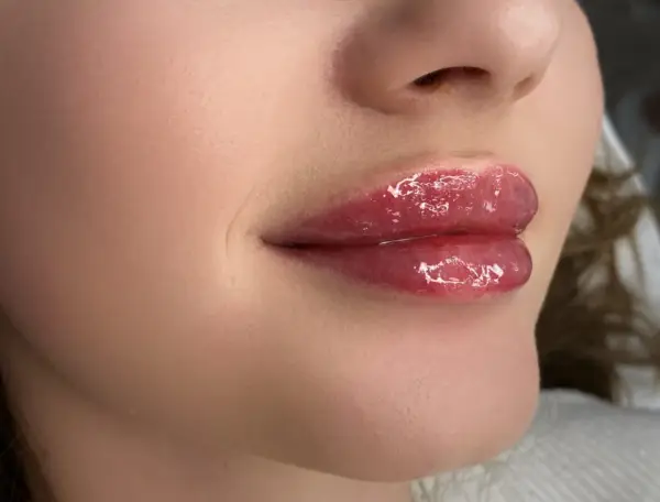 Błyszczące, pełne usta baby doll po zabiegu makijażu permanentnego.