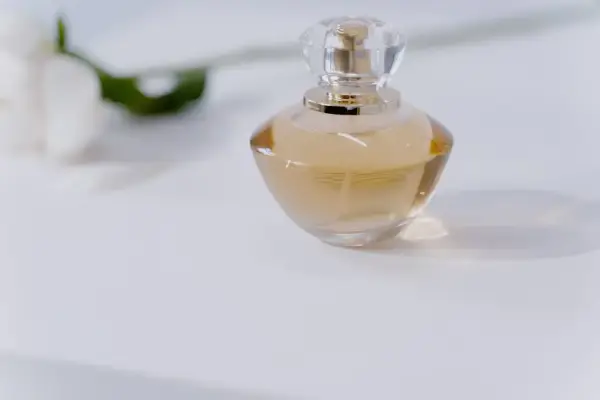 Elegancka butelka perfum na białym tle. Chcesz wiedzieć, jak sprawdzić, czy perfumy są oryginalne? Zwróć uwagę na detale.