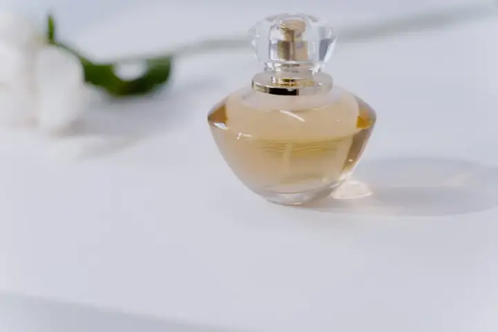 Elegancka butelka perfum na białym tle. Chcesz wiedzieć, jak sprawdzić, czy perfumy są oryginalne? Zwróć uwagę na detale.